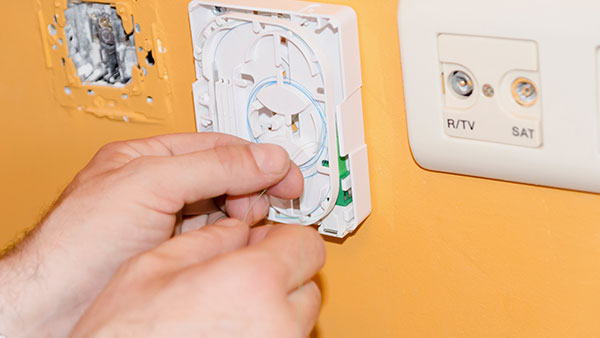 Person installing internet in a wall.